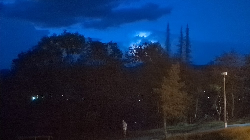 Landscape with sky during the late evening, a cloud illuminated by   lightning can be seen.