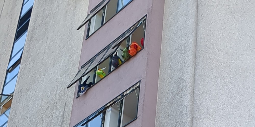 Four inflatable creatures looking out of windows of the hotel.